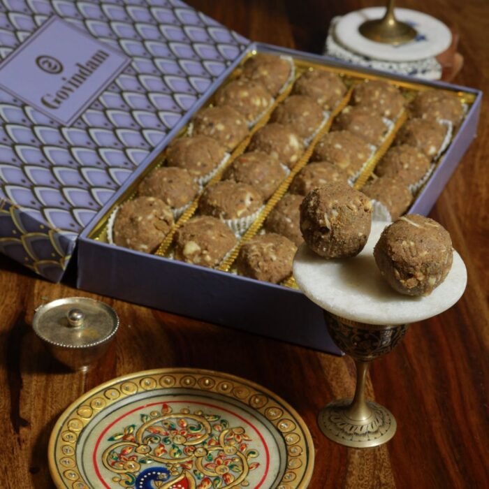 Golden-brown Balwan laddu balls garnished with almond slivers on brass thali