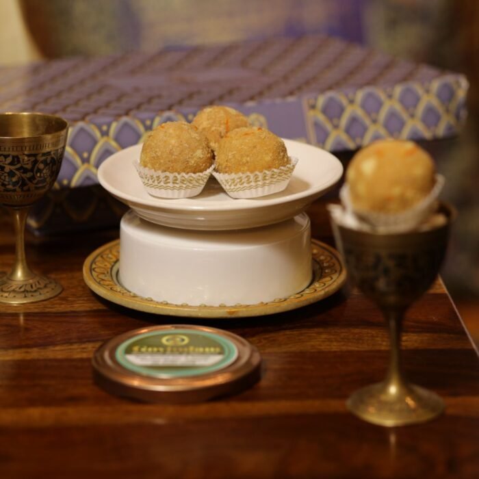 Stack of besan laddus garnished with pistachio slivers on decorative silver platter