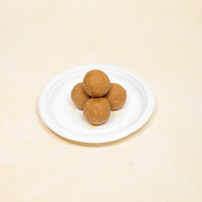 Cross-section of besan laddu revealing smooth, grainy texture on white plate