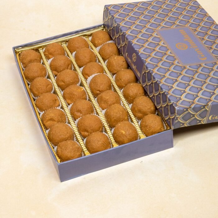 Golden-brown besan laddu balls dusted with cardamom powder on brass thali