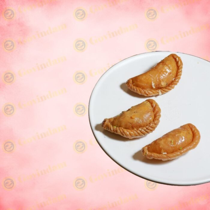 Colorful gujiyas decorated with edible silver and gold leaf, arranged in a circular pattern