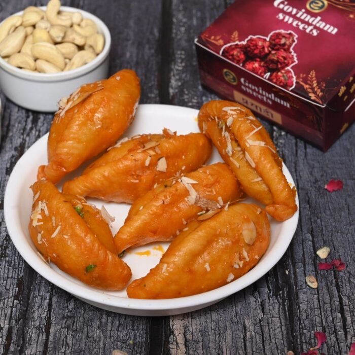 Gujiyas being shaped and filled by hand, with a tray of prepared ones nearby