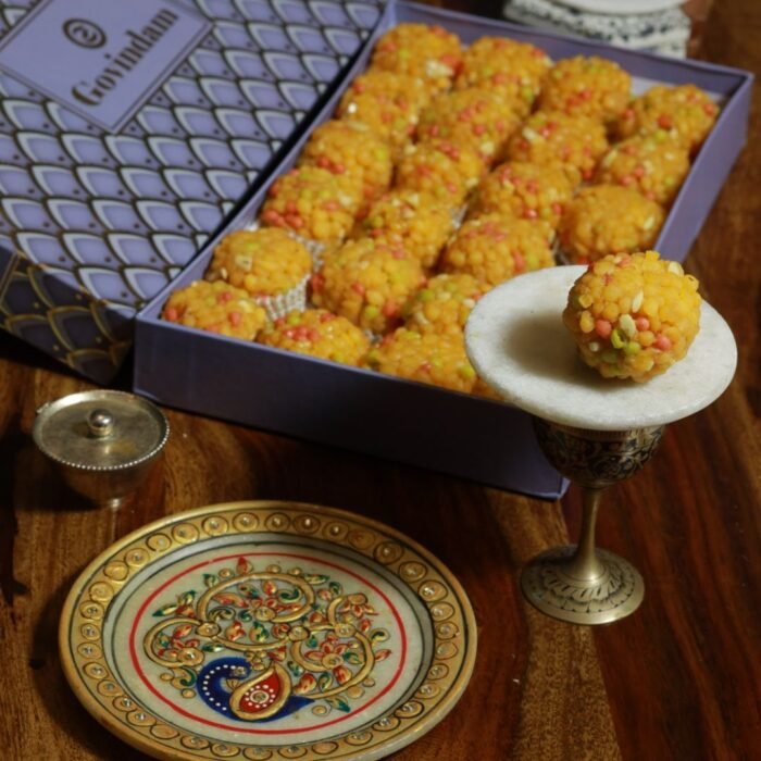 Chogani laddus arranged in a circular pattern with sprinkled cardamom powder