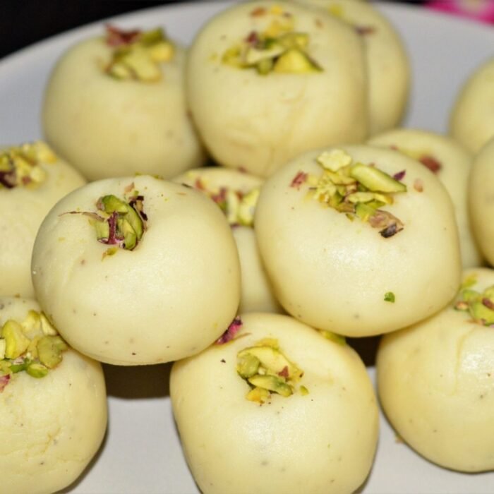 Mini doodh pedas stacked in clear glass jars with saffron strands and pistachio garnish