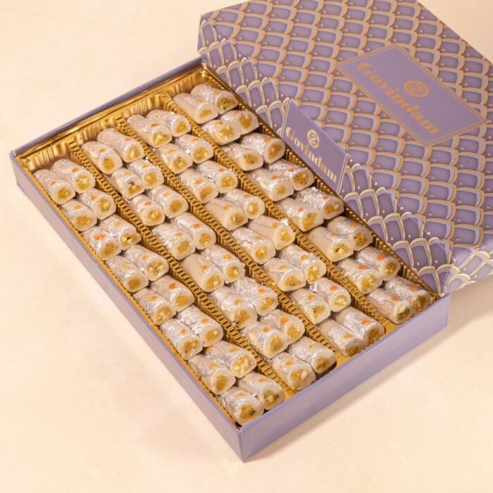 Assorted mini kaju rolls in various flavors, arranged in a spiral pattern with edible flower garnishes