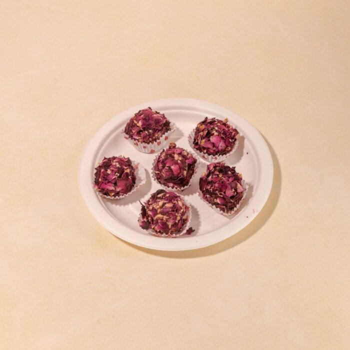 Rose laddus being shaped by hand, with rose water, gulkand (rose petal preserve), and natural pink coloring visible